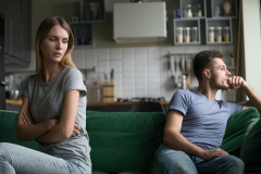 Offended upset man and woman sitting separately on couch